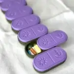 Set of purple pill lids with symbols for days of the week on a green base