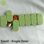A small-sized 3D printed weekly pill box shown in a single solid color, featuring seven compact containers with smooth sliding lids. Each lid includes an engraved sun and day-of-week marking. The pill box is lightweight, travel-friendly, and designed for daily medication organization. Displayed on a clean background to show the shape, texture, and single-color style clearly.
