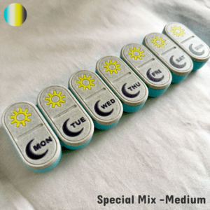 A medium-sized 3D printed weekly pill box set in a special mix color combination, featuring vibrant custom lids such as yellow sun-and-moon patterns, turquoise, pink, or multicolor styles. The photo highlights the unique color blend chosen by the customer, with engraved weekday labels and smooth sliding lids. Ideal for gifting, chronic illness management, or adding fun to medication routines.
