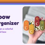 Hand holding a 7-day AM/PM pill organizer with seven different fall-colored lids and sun and moon icons