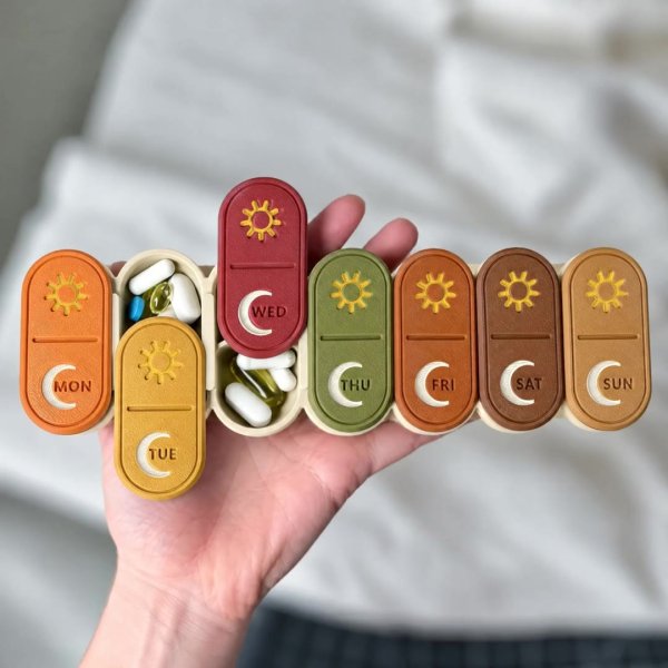 USACUTTIE fall pill organizer with special mix lids, gold sun and ivory moon, held in one hand with two lids slid open